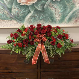 Red rose casket spray with a red ribbon bow