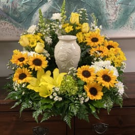 Yellow sunflowers and roses arranged around a white vase