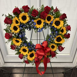 Heart-shaped wreath of red roses and sunflowers with a red bow