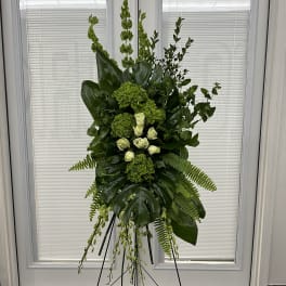 Tall green floral standing spray on an easel with white roses