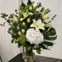 White lilies and hydrangea in a clear glass vase