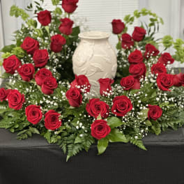 Red roses arranged around a white vase centerpiece