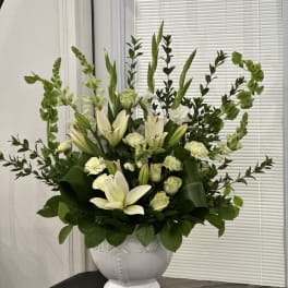 White lilies and pale carnations in a white urn vase