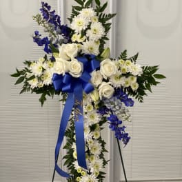 White and blue floral cross on a stand with a ribbon