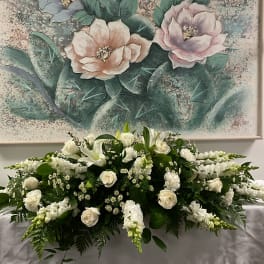 Low white floral arrangement with roses and lilies on a table