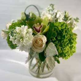 Green and white bouquet with roses and orchids in a glass vase