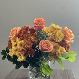 Peach roses and yellow chrysanthemums in a square glass vase
