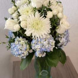 White and pale blue flowers arranged in a glass vase