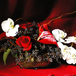 Red roses and white orchids arranged in a low glass bowl