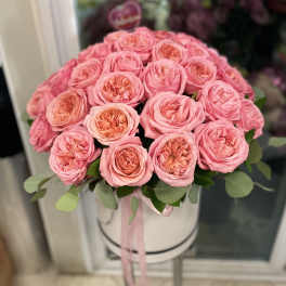 Pink roses arranged in a round white hat box with a ribbon