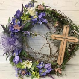 Floral wreath with purple and white flowers and a wooden cross