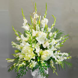 Tall white floral arrangement in a white pedestal vase