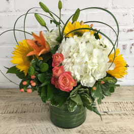 Bouquet of sunflowers, white hydrangea, pink roses, and orange lilies in a green vase