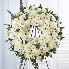White floral funeral wreath on a black stand