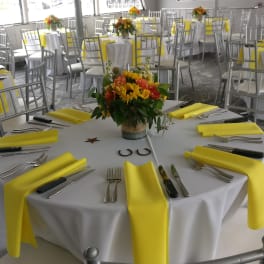 Round banquet tables with yellow napkins and floral centerpieces