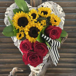 Heart-shaped bouquet of sunflowers and red roses with a striped ribbon