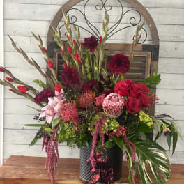 Large mixed floral arrangement in a black vase with red and pink blooms