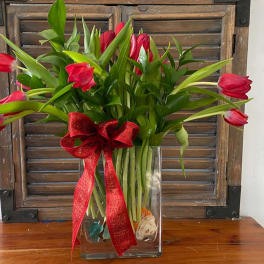 Red tulips in a clear glass vase with a red ribbon