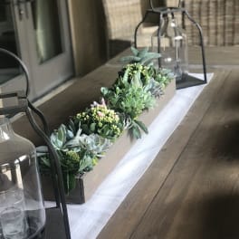 Succulent centerpiece in a long rectangular box with lanterns on a table