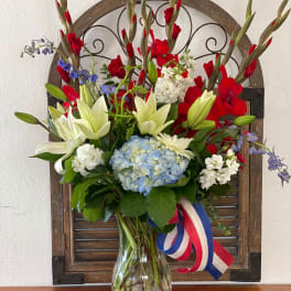 Mixed bouquet with lilies, hydrangea, and red gladiolus in a glass vase