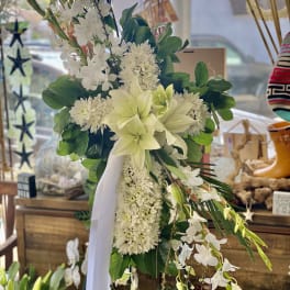 White floral standing spray with lilies and orchids on a ribboned easel