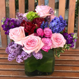 Mixed bouquet of pink, purple, and red flowers in a green vase