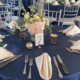 Floral centerpiece on a navy-draped table with folded cream napkins