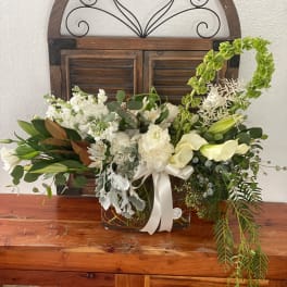 White floral arrangement in a glass vase with a ribbon