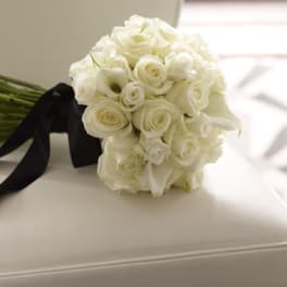 White rose bouquet with black ribbon on a white chair