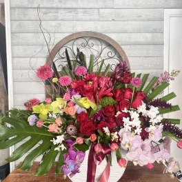 Large mixed floral arrangement in a white vase with pink, red, and white blooms