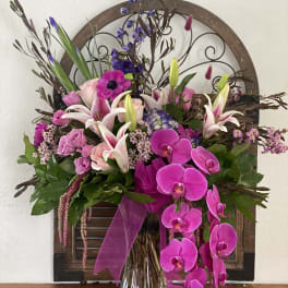 Pink and white floral arrangement in a glass vase with orchids and lilies