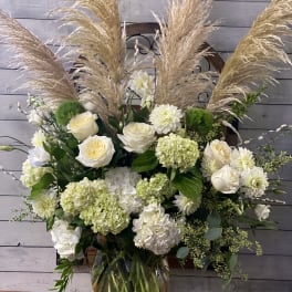 White floral arrangement with pampas grass in a glass vase