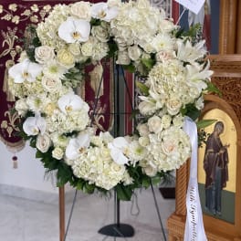 White floral heart wreath on a stand with orchids and roses