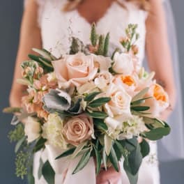 Bridal hand-tied bouquet of peach and cream roses with white blooms and ribbon wrap
