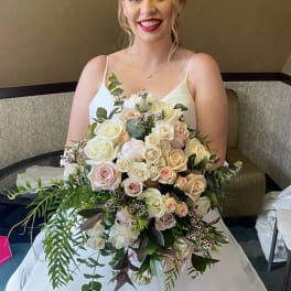 Bride holding a large bouquet of white and blush roses