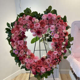 Heart-shaped floral wreath of pink and red roses on a stand