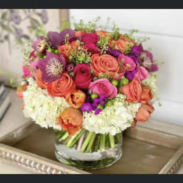 Mixed pink, coral, and purple bouquet in a clear glass vase
