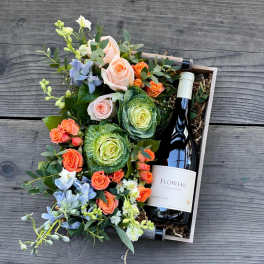 Floral gift box with roses, cabbage roses, and a wine bottle