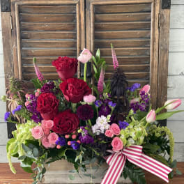 Mixed bouquet of red and pink roses with purple accents and a striped ribbon