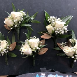 Small white rose boutonnieres with baby's breath and green leaves