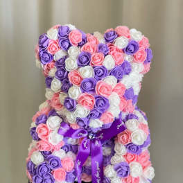 Teddy bear made of pink, purple, and white roses with a purple ribbon