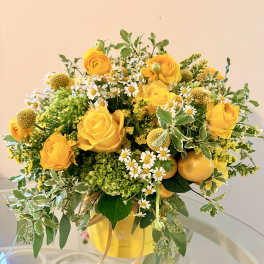Yellow roses and small white daisies arranged in a yellow vase