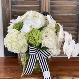 White floral arrangement with orchids and hydrangeas in a glass vase