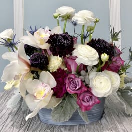 Mixed bouquet in a blue container with white, pink, and purple flowers