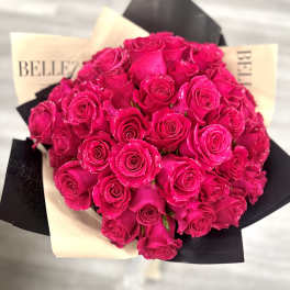 Bouquet of bright pink roses wrapped in black and cream paper