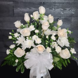 White roses and chrysanthemums arranged with a white ribbon bow