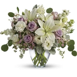 Lavender roses and white lilies in a clear glass vase