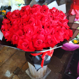 Large bouquet of red roses wrapped in black paper with a red ribbon