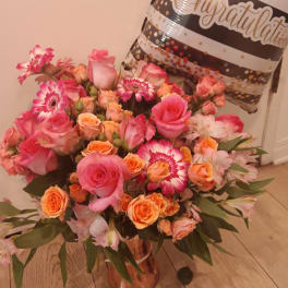 Pink and orange mixed bouquet in a vase with a congratulatory balloon