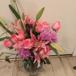 Pink roses and lilies in a glass vase with purple mums